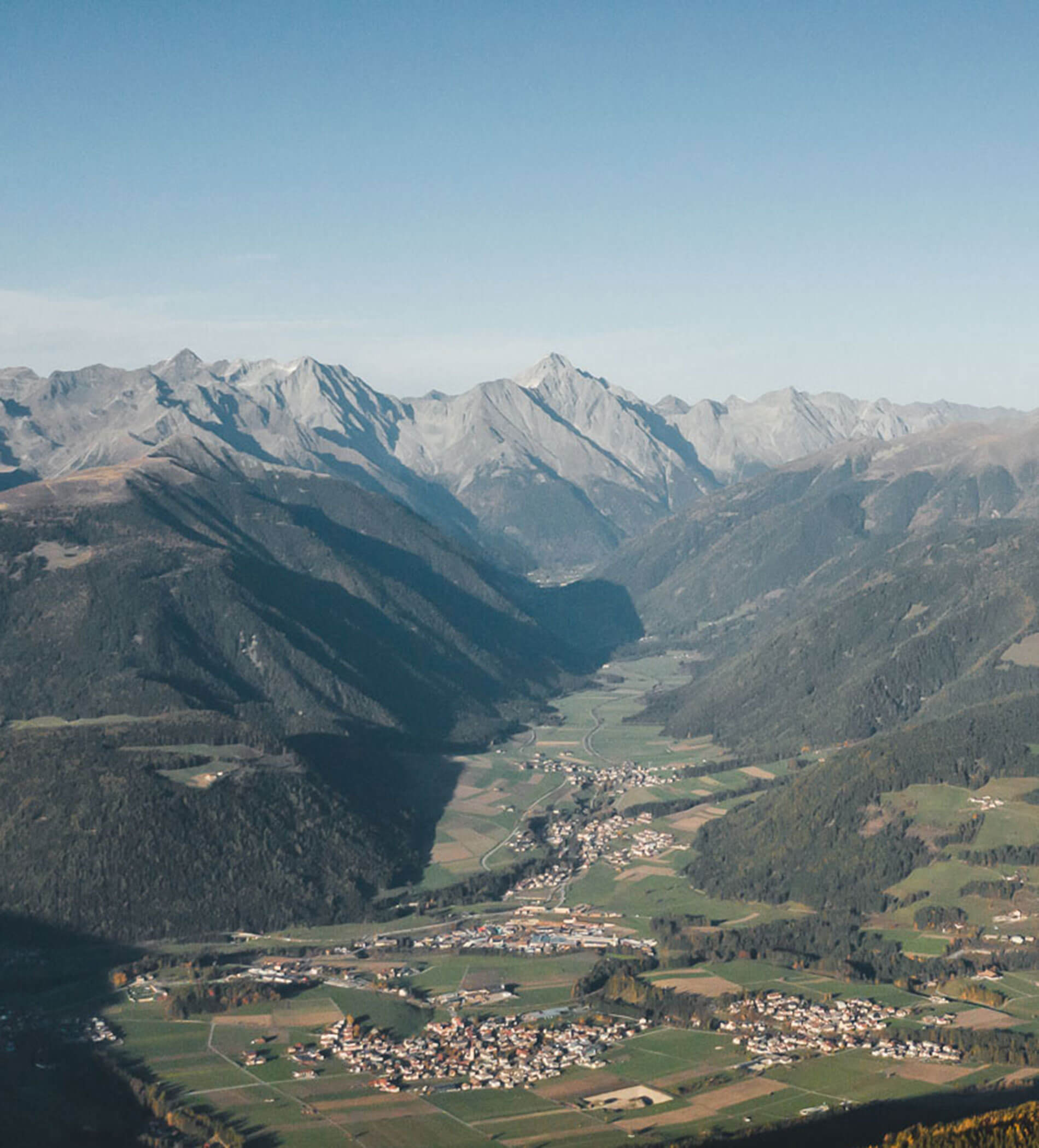 Ein Tal mit kleinen Dörfern, Feldern und Bergen unter einem strahlend blauen Himmel. - Ampark